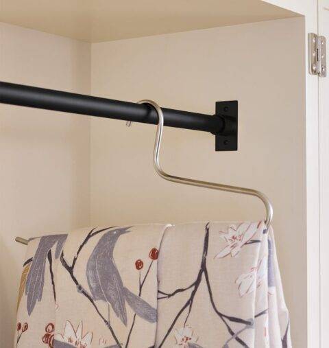 A tension rod holding a blanket folded on a hanger