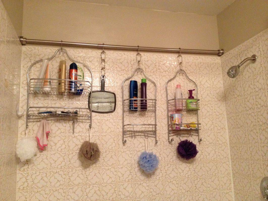 A tension rod holding four different shower caddies against the wall.