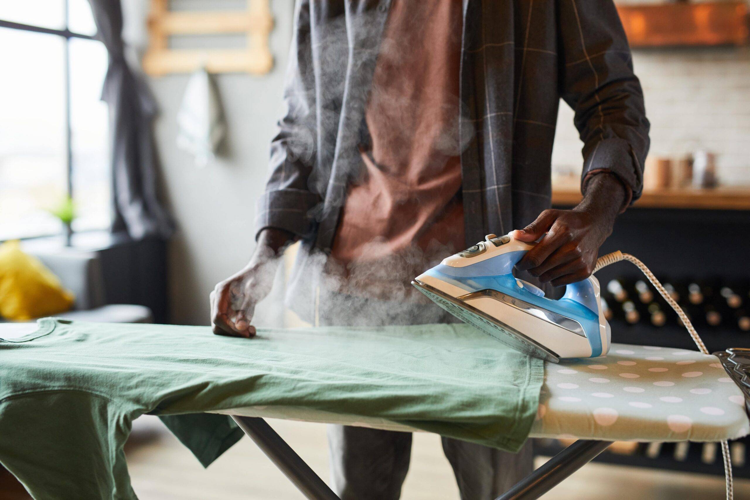 A man ironing a shirt with the steam setting on.