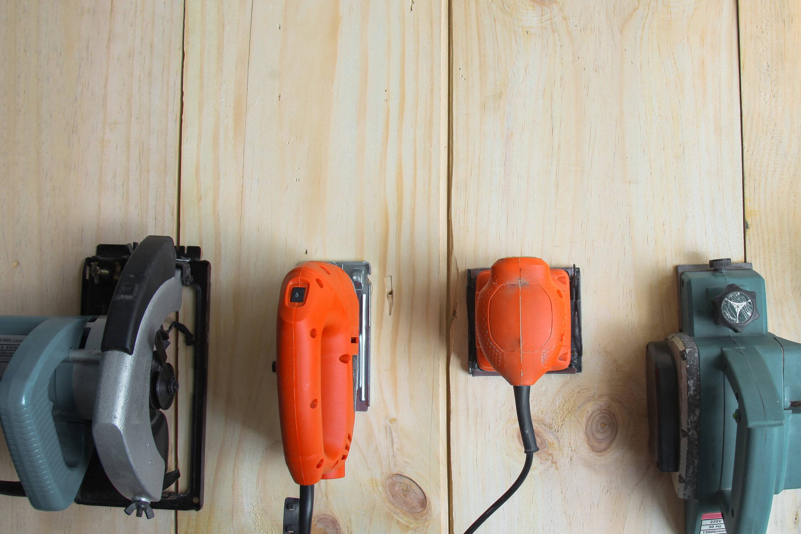 An above view of four power tools lined up against a wood surface.
