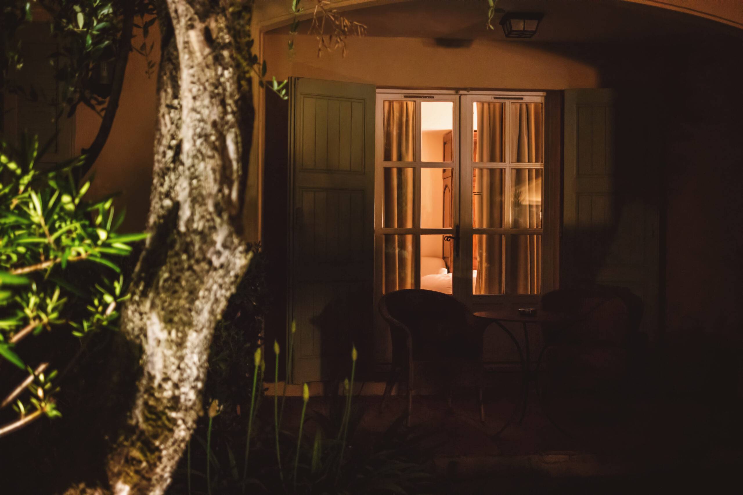 A window in the backyard of a house at night, the lights inside are on.