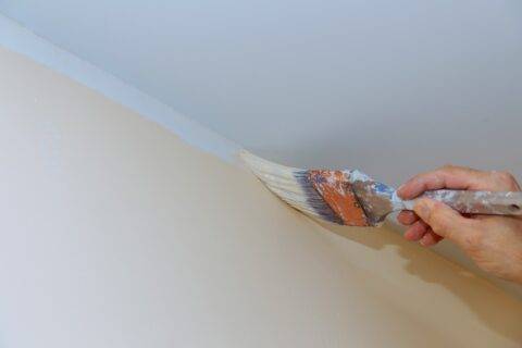 Hand holding brush painting color to the angle walls and ceilings