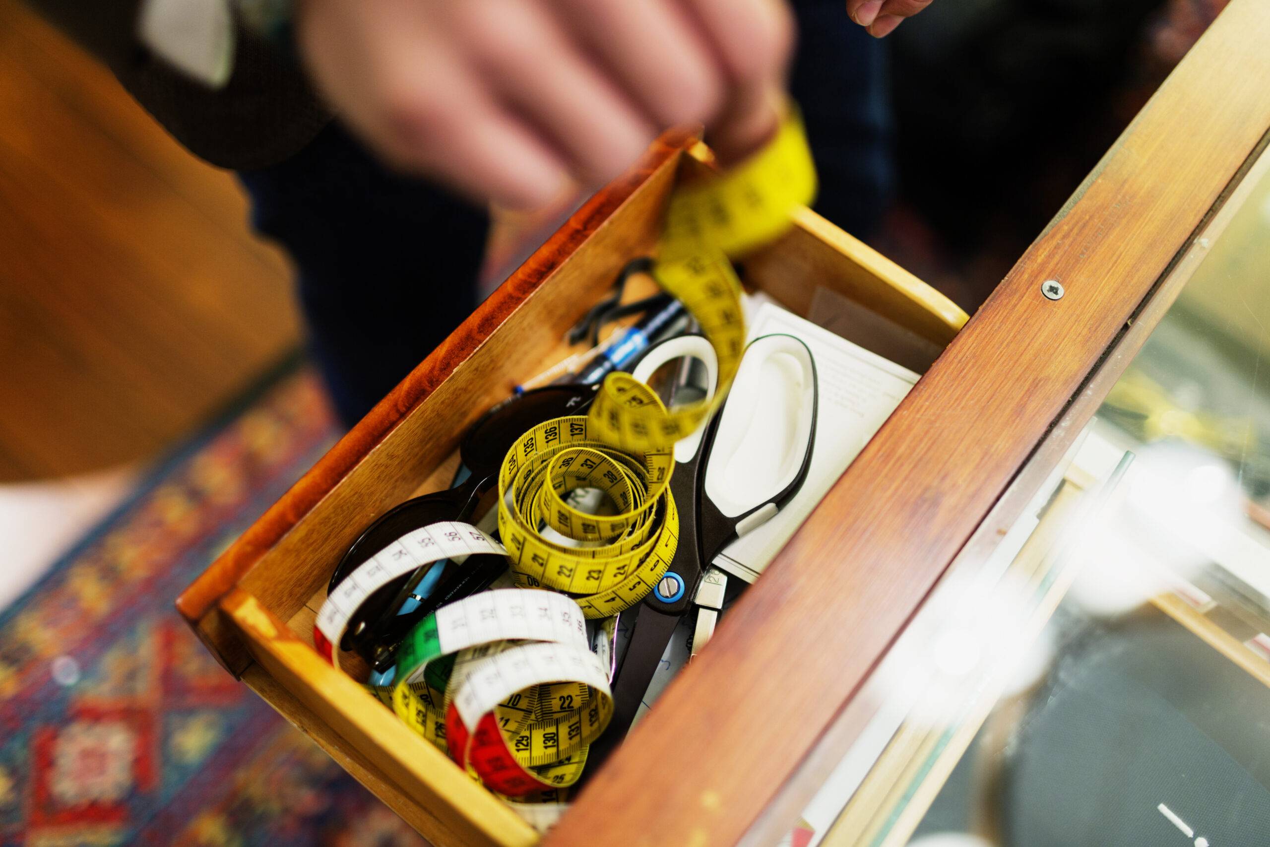 Hands rummaging through a drawer full of sewing items