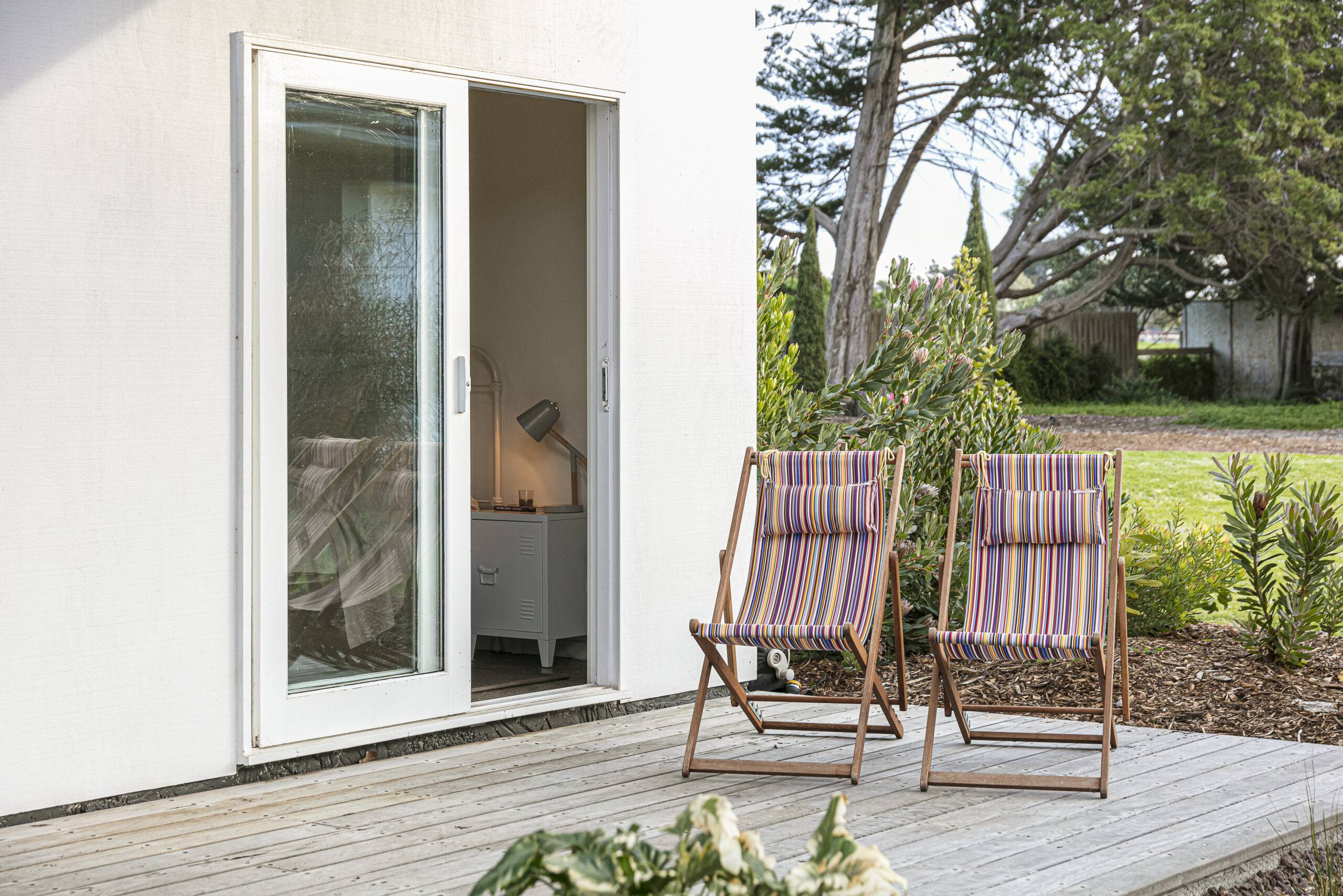 A home's back porch, the sliding door open and two lawn chairs just outside.