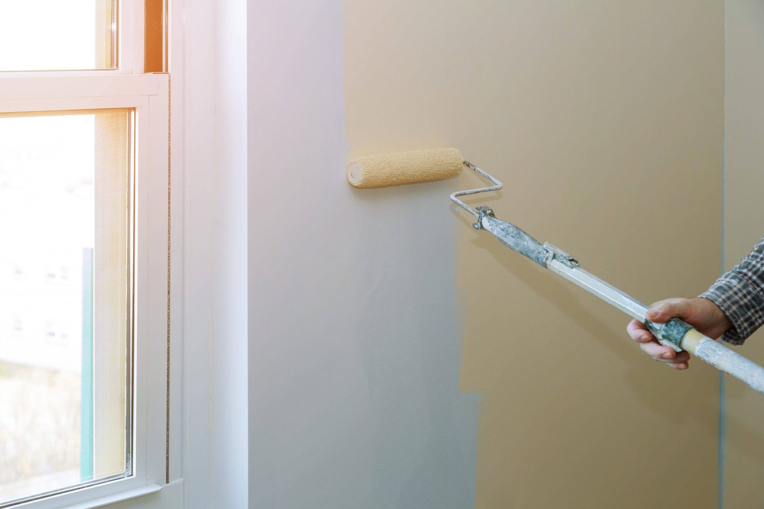 Painting male hand walls with paint roller apartment, renovating with color paint