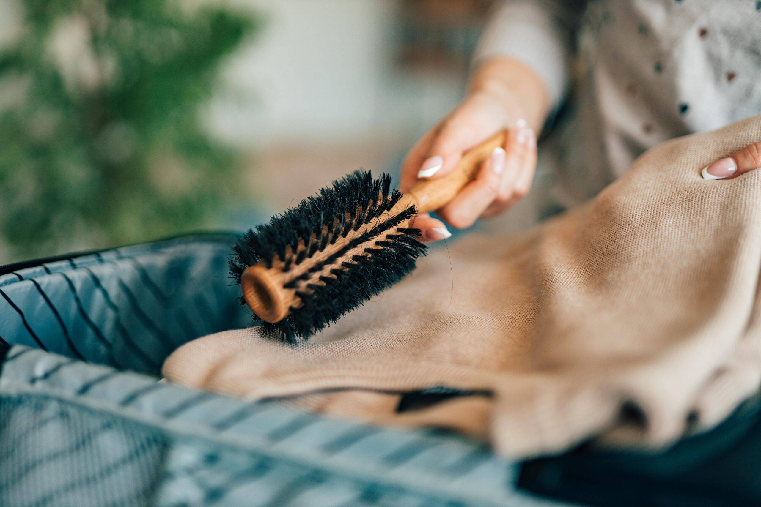 A hand pulling a ground brush out of a suitcase.