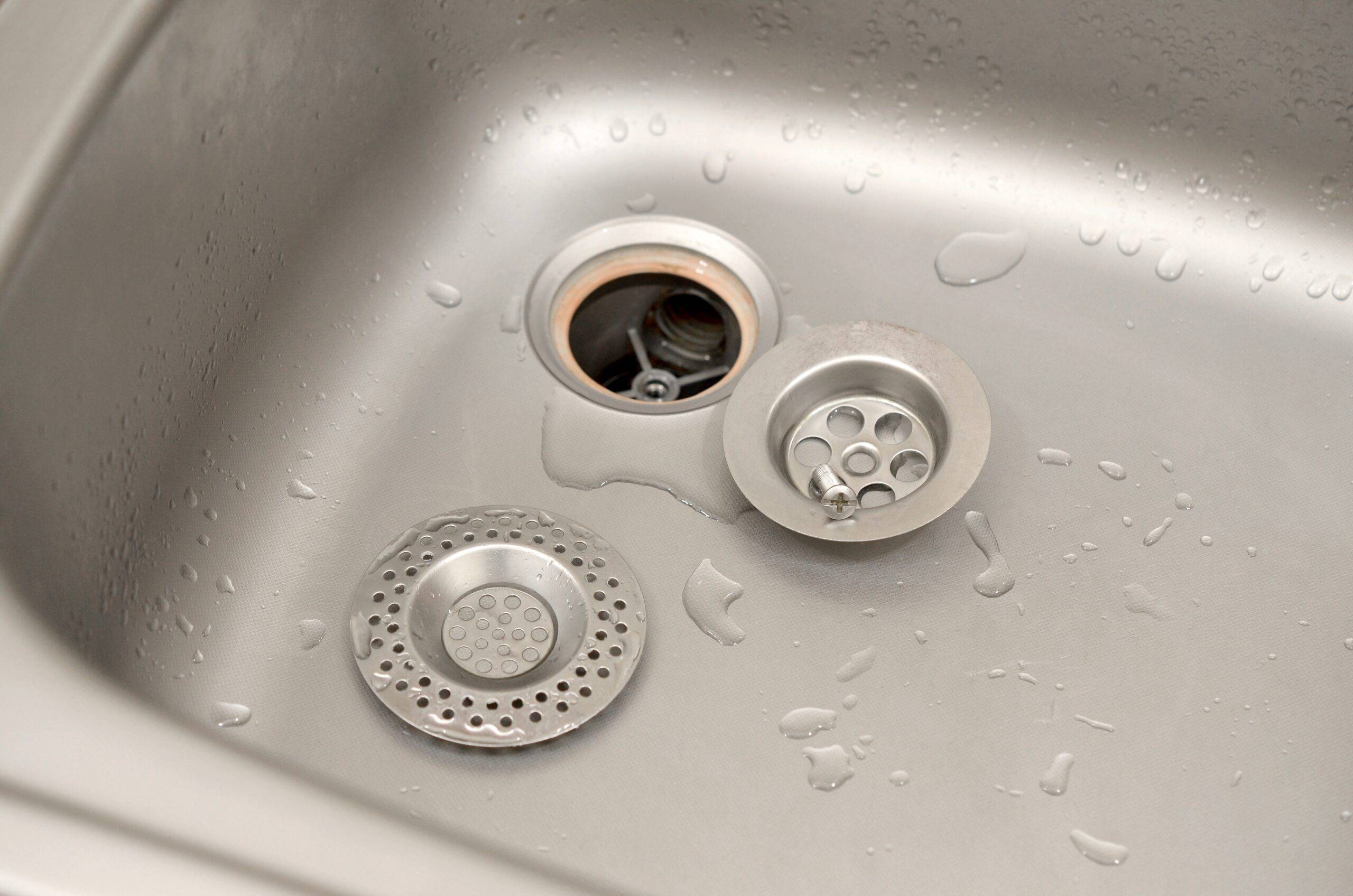 Silvery kitchen sink with a disassembled protective filter. Kitchen sink repair process