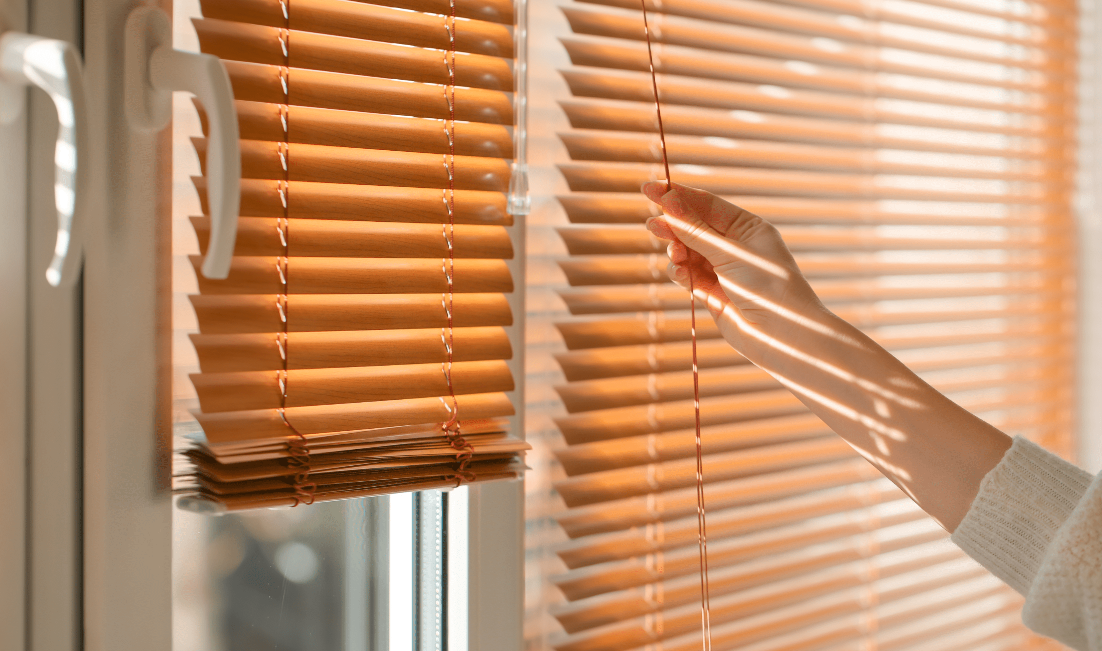 A hand closing a set of blinds.