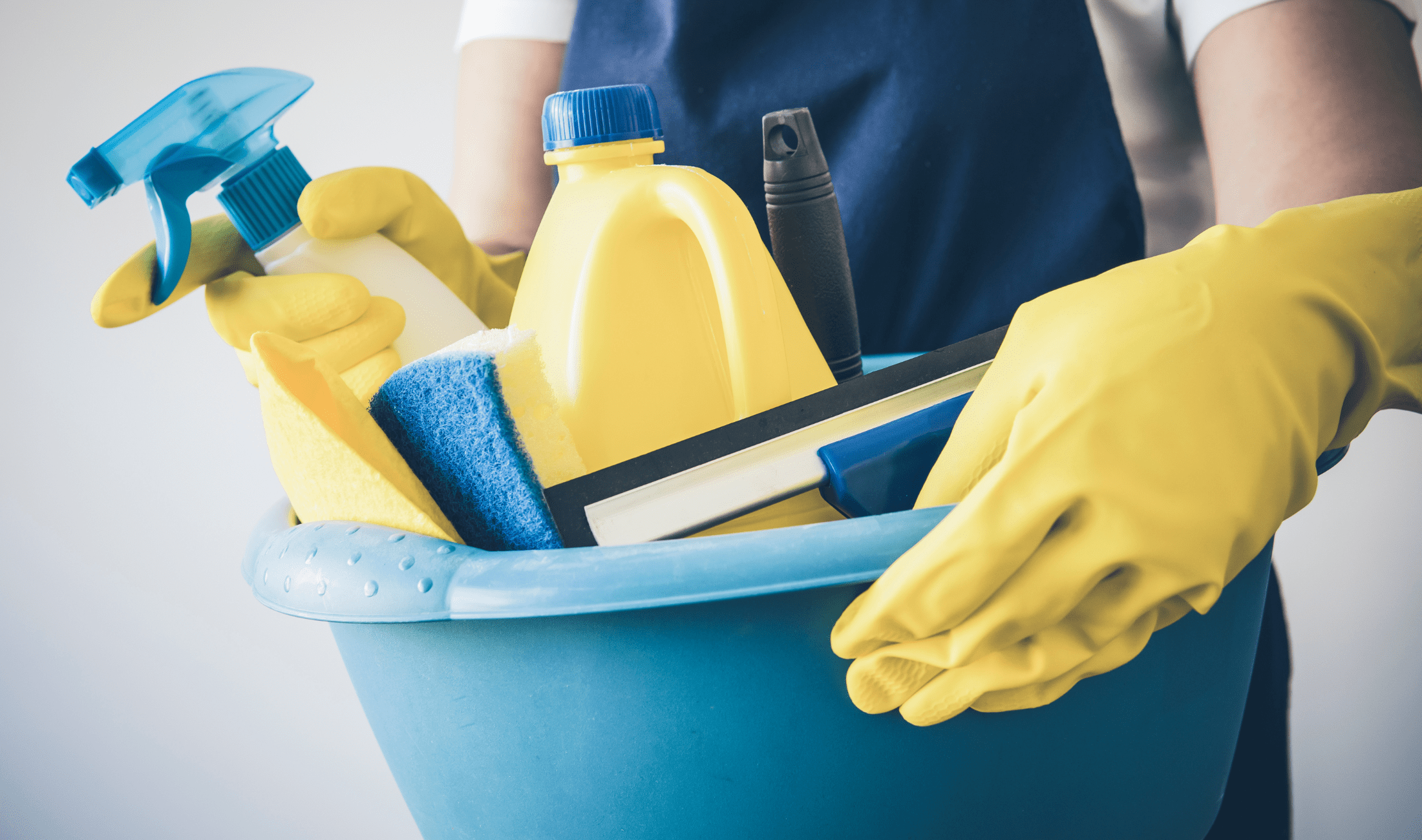 A person holding a bucket of cleaning supplies.
