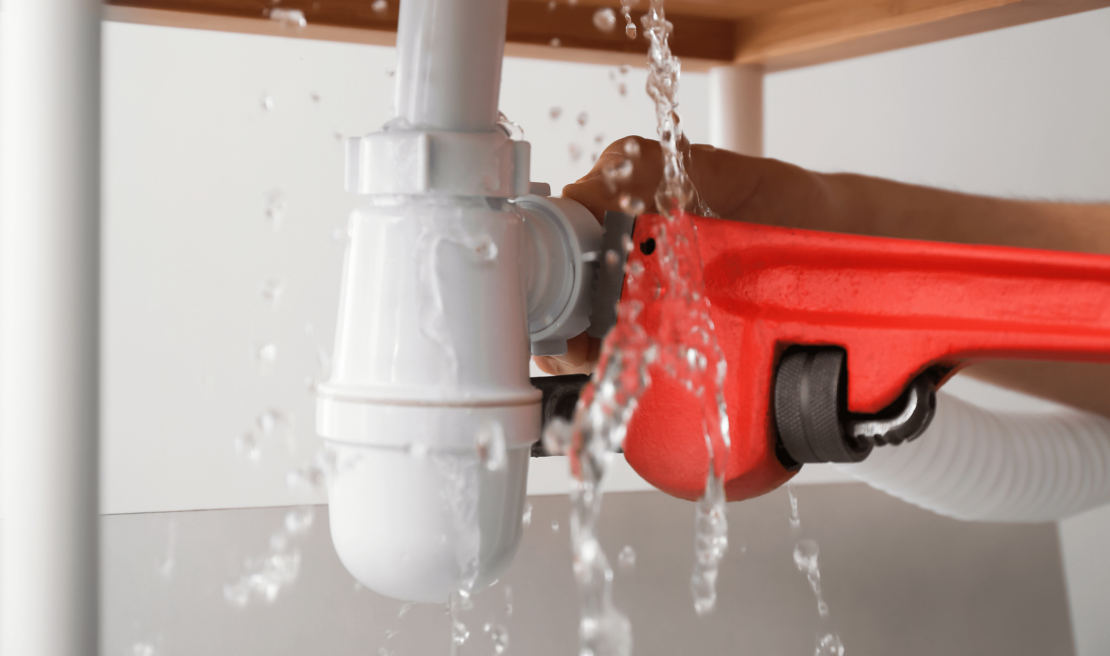 A close photo of an adjustable wrench trying to tighten a leaking faucet.