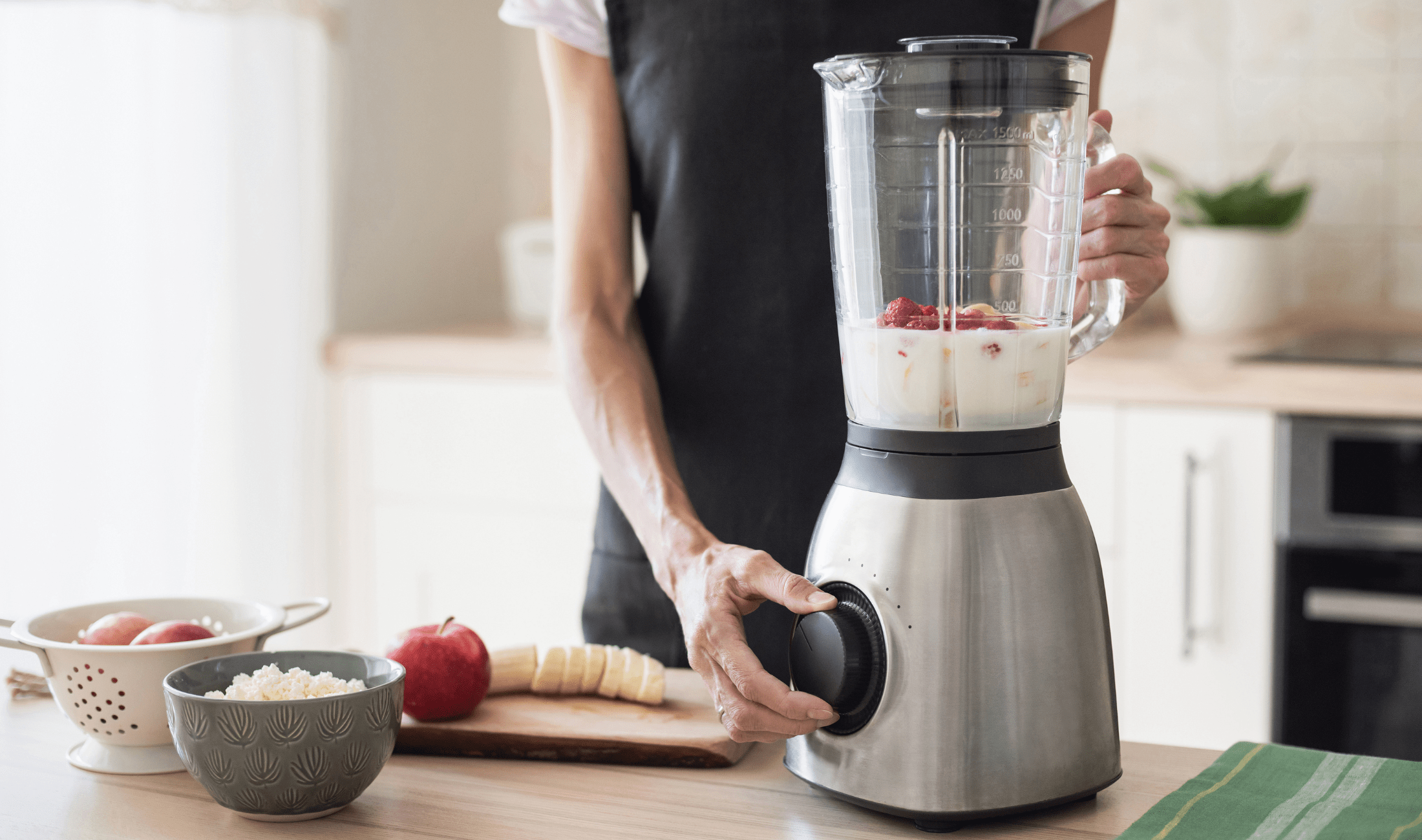 A person using a blender to mix some fruits.