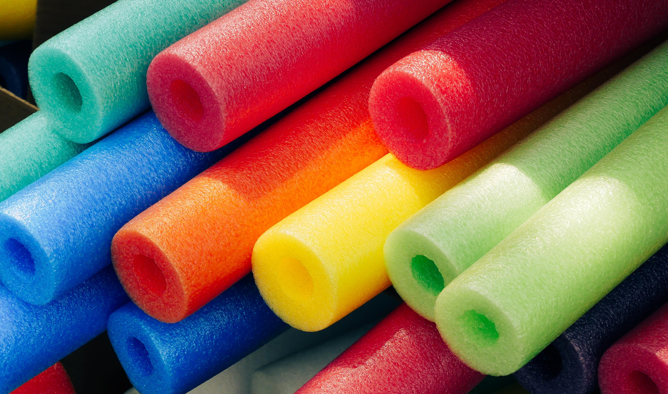 A close photo of a collection of colorful pool noodles.