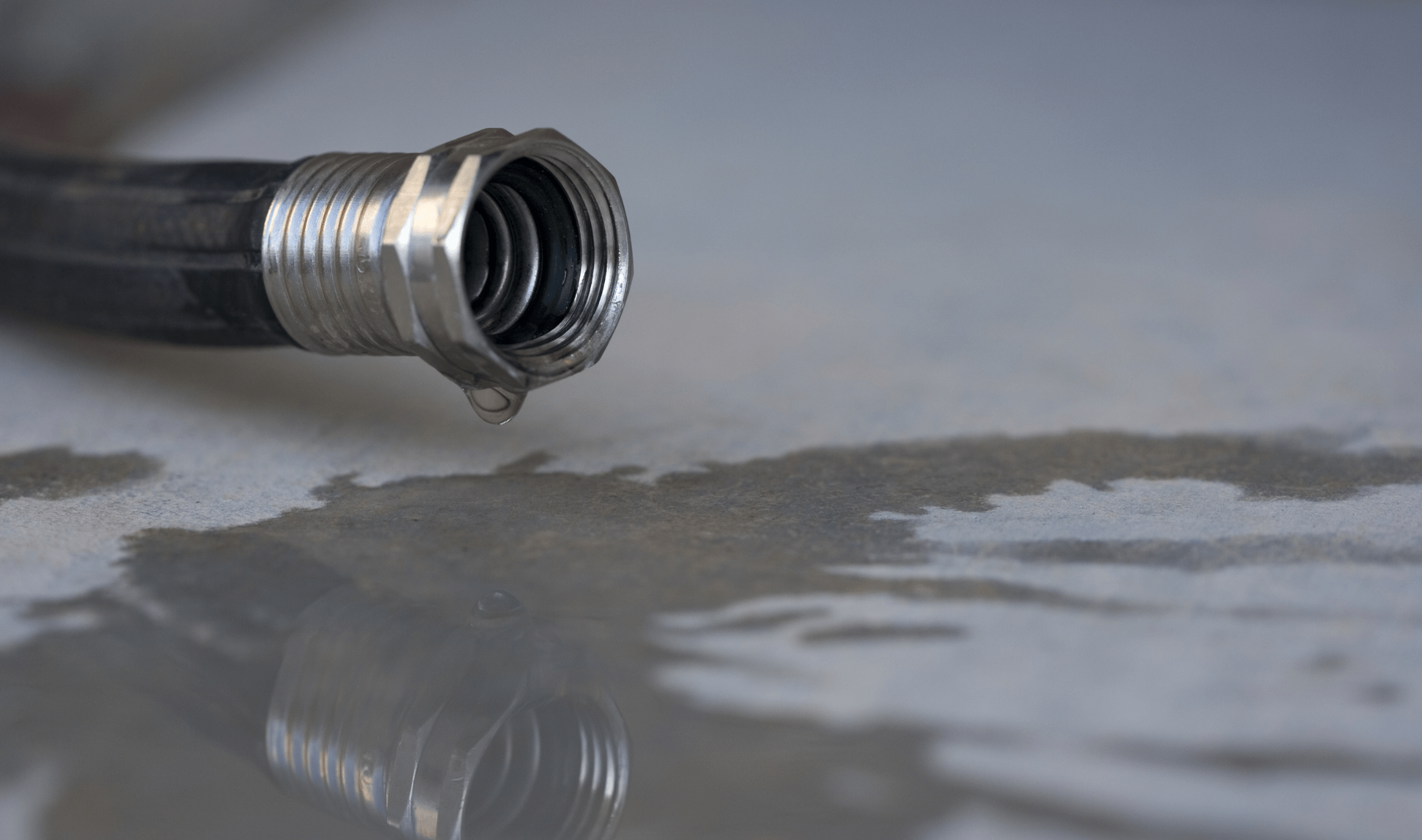 A leaking hose on a concrete ground.