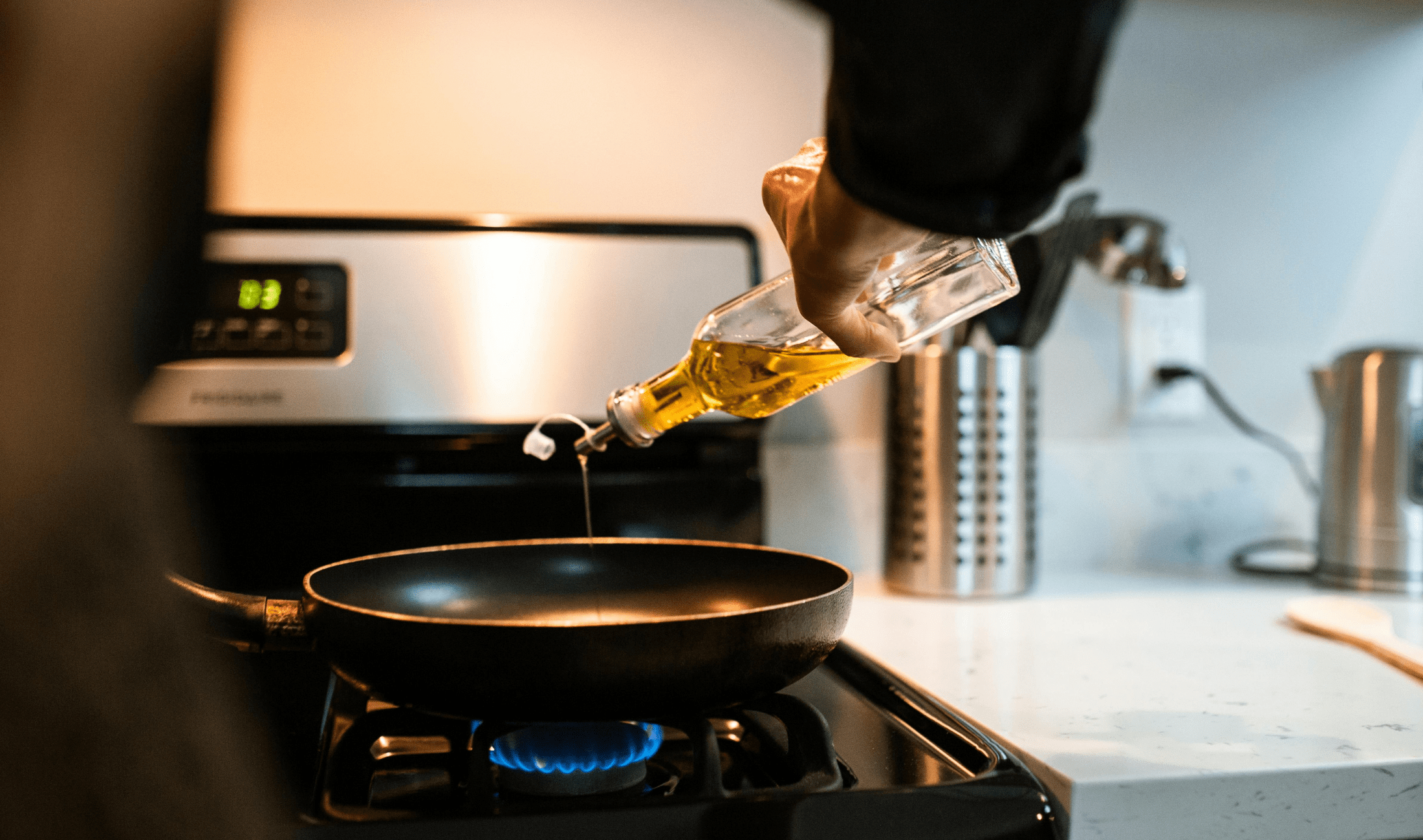 A person pouring some cooking oil into a pan.