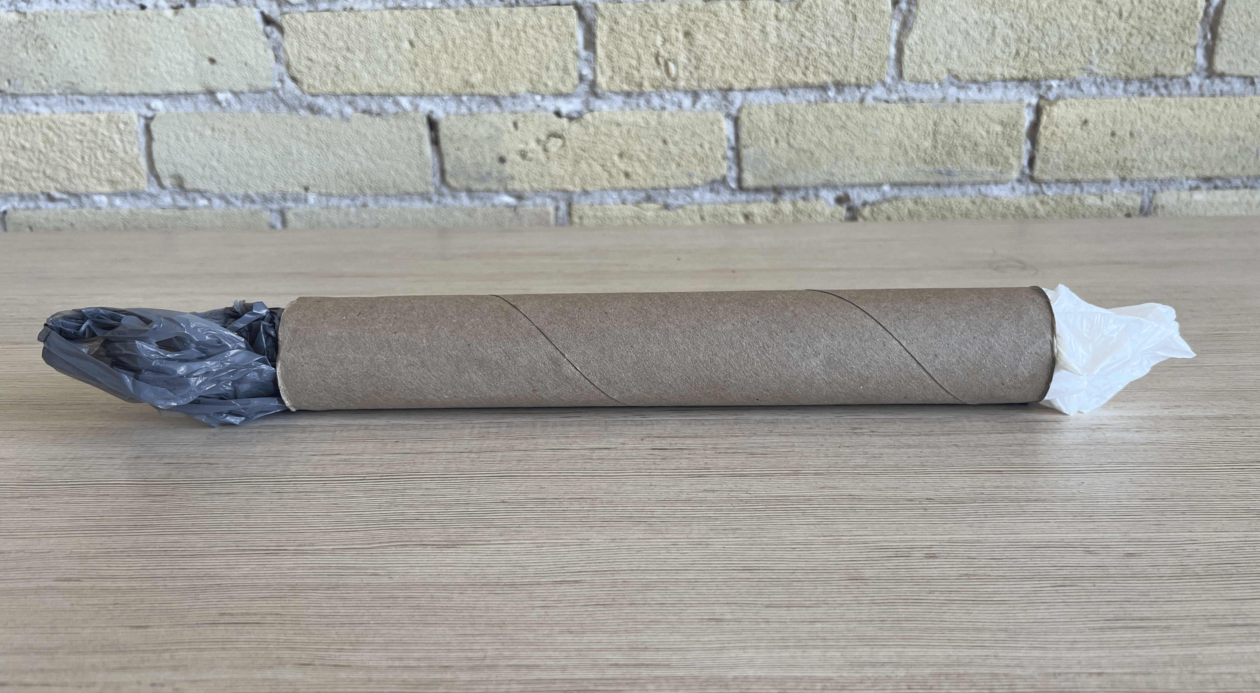 A paper towel roll with plastic bags sticking out each end.