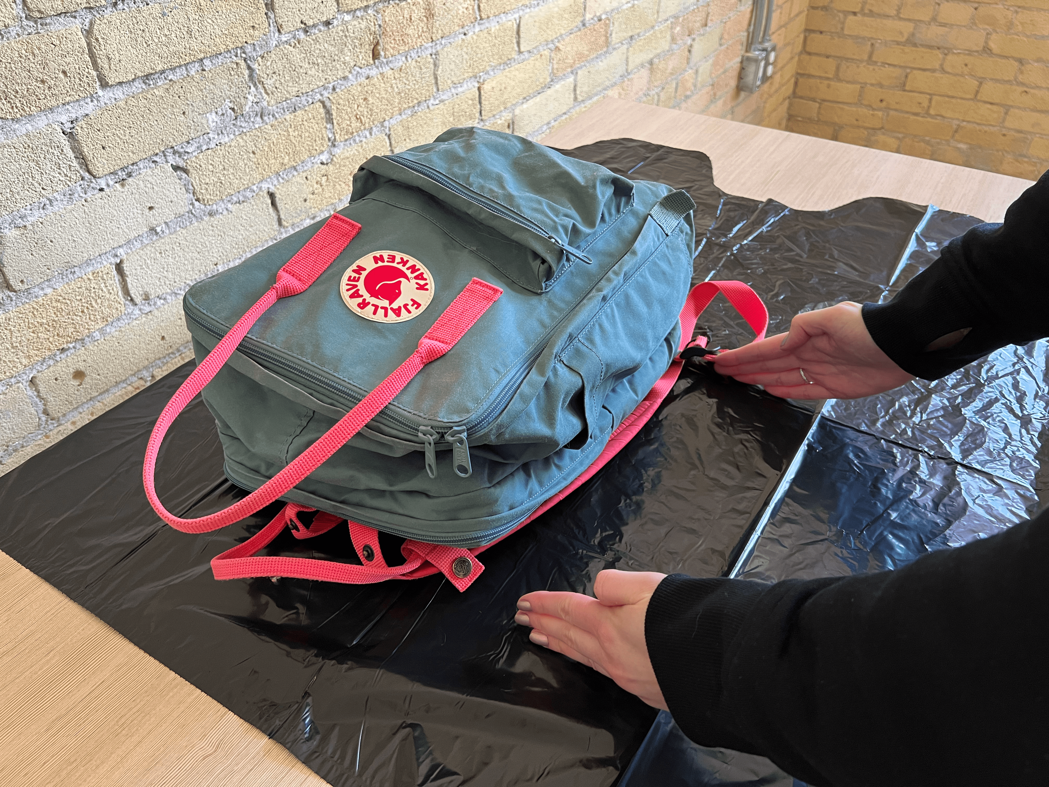 A pair of hands measuring the length of a backpack's straps.