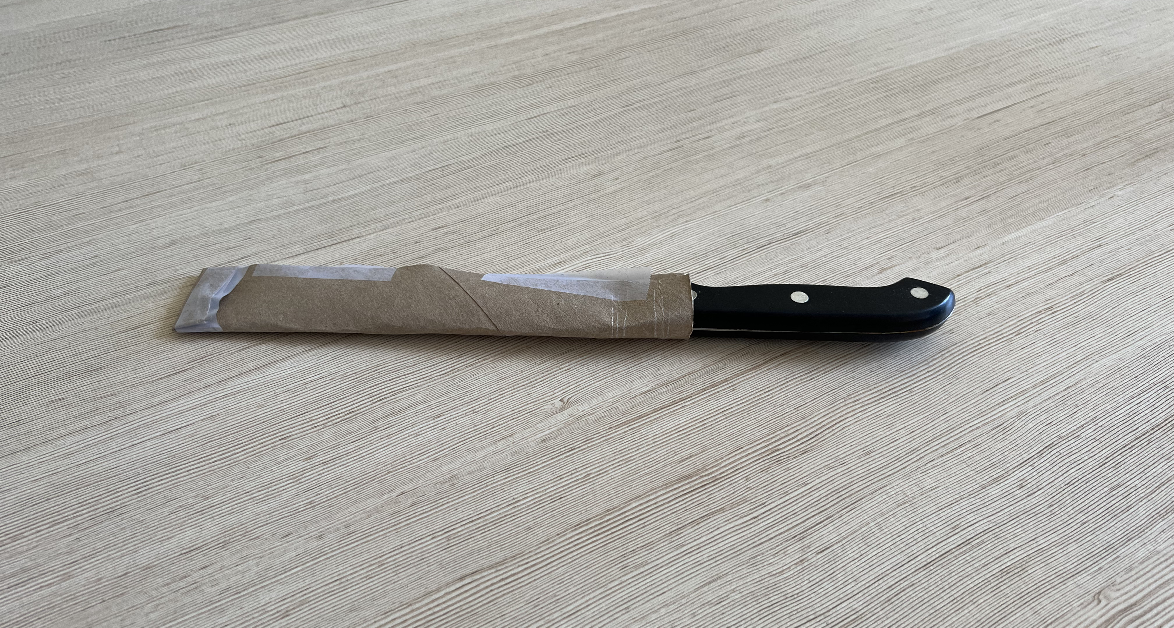 A knife with a sheath made up a cut and taped cardboard tube.