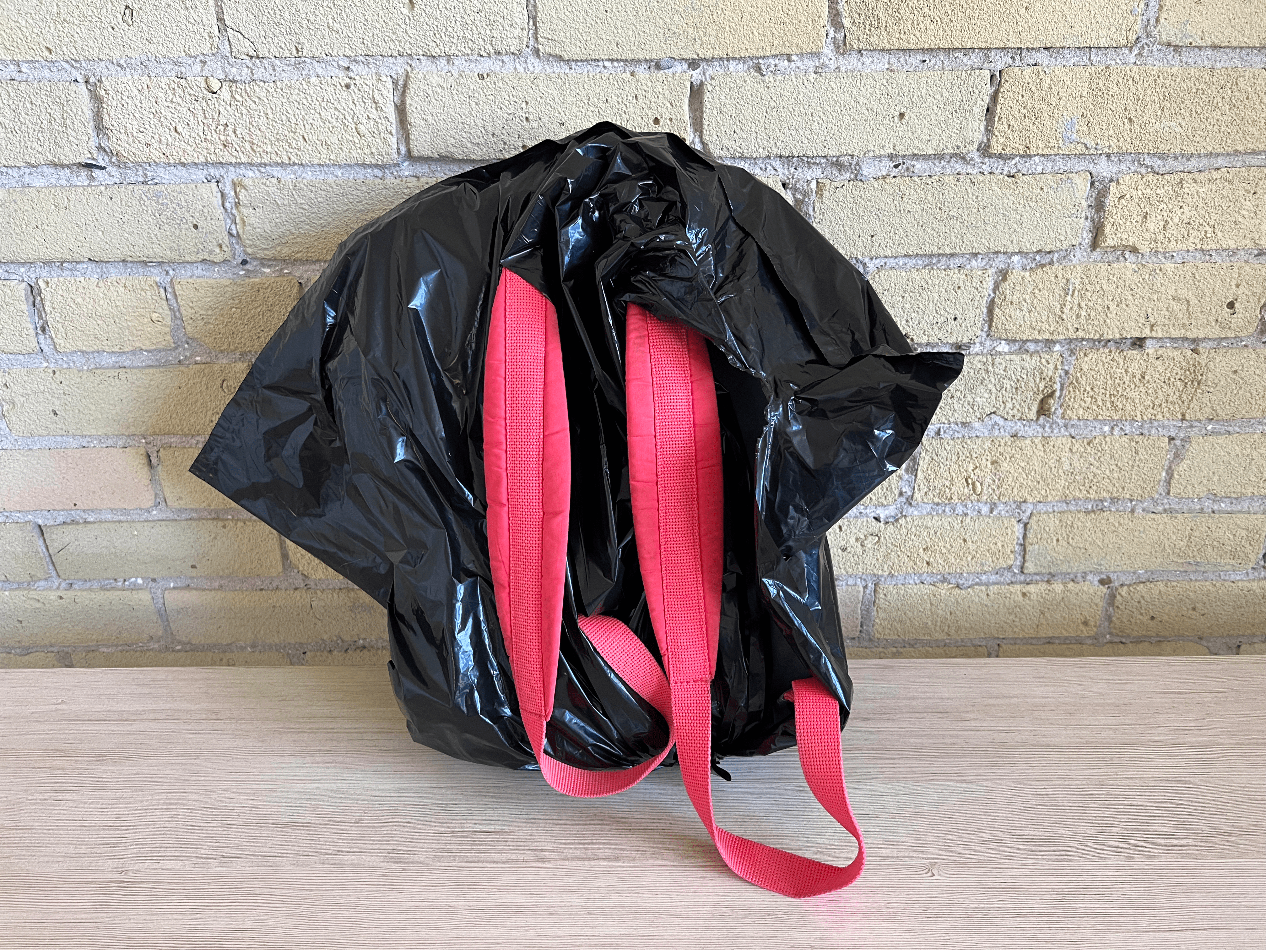 A backpack covered in a garbage bag with the straps sticking out.