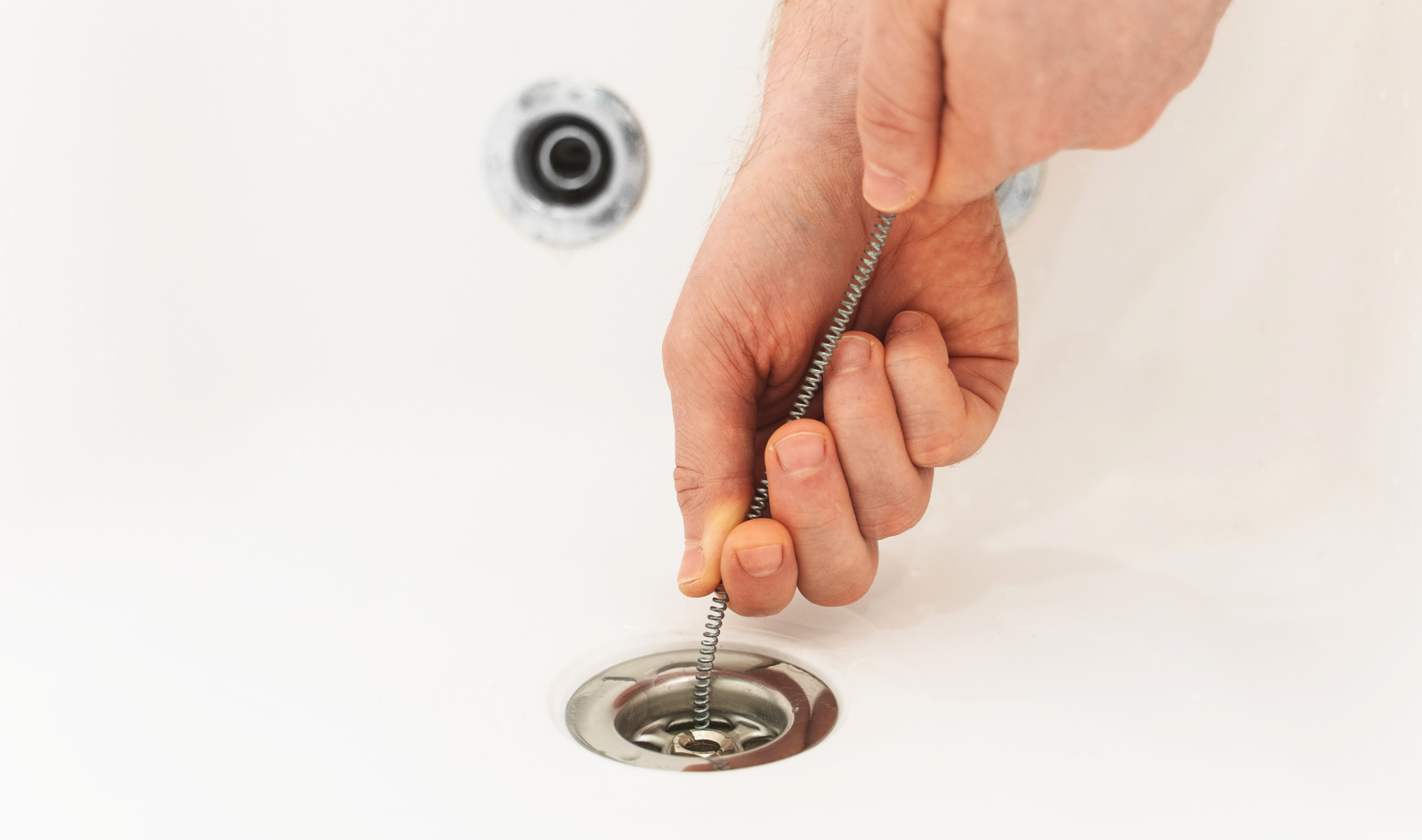 A close photo of a someone using a drain sink in a bathroom sink.