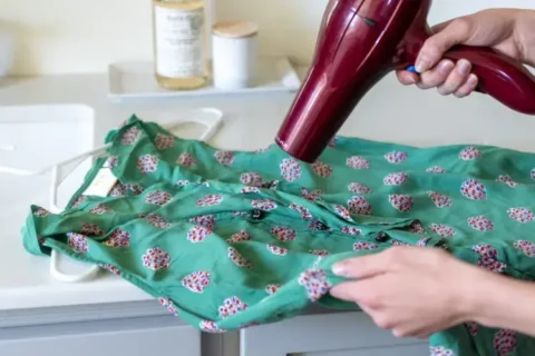 Someone using a hair dryer on a dress.